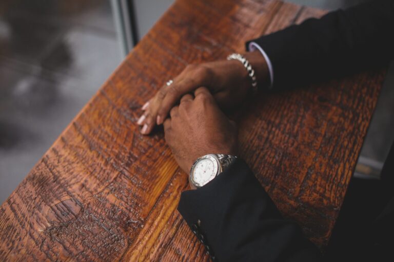 Hands folded and resting on a wooden table